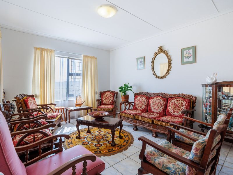 A well-maintained living room featuring neutral tiled flooring and a central ceiling light fixture, offering a functional and traditional living space.