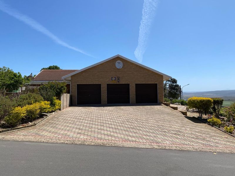 Front view of a well-maintained brick house featuring a spacious triple garage and a neatly paved driveway.