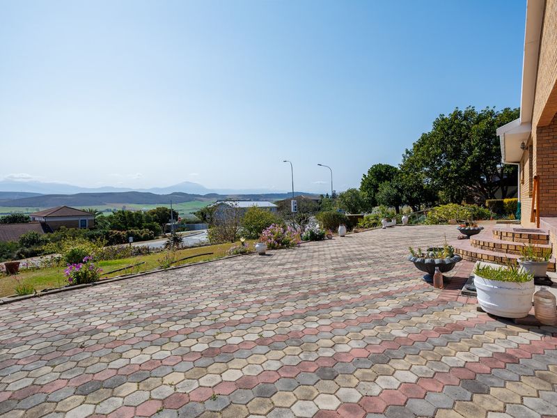 A spacious paved patio area featuring brick construction and steps, offering expansive views of the surrounding landscape and neighborhood.