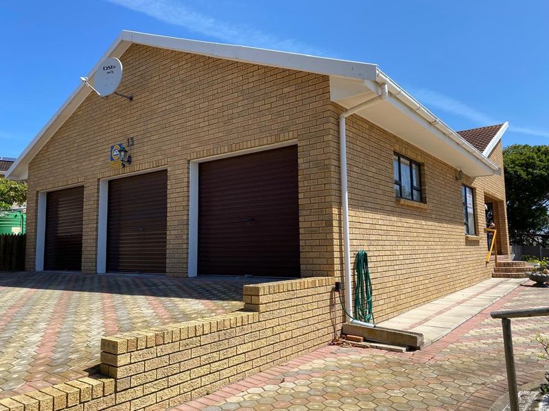 A well-maintained triple garage with a brick facade and paved driveway, featuring integrated security and satellite infrastructure.
