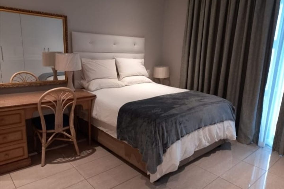 A well-maintained bedroom featuring tiled flooring, a built-in wardrobe, and a sliding door providing access to natural light.