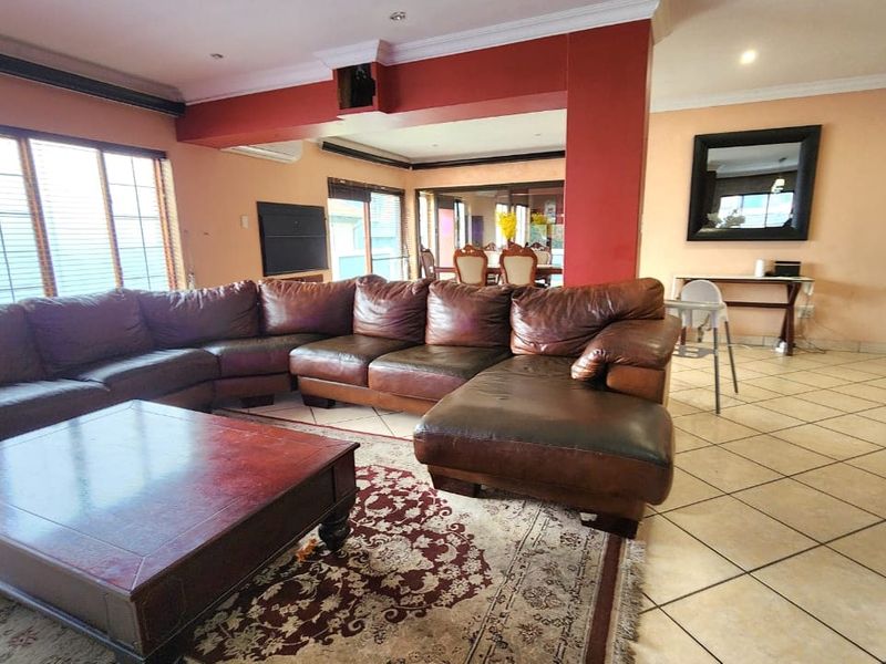 Spacious open-plan living area featuring tiled flooring, recessed lighting, and an integrated air conditioning unit, connecting to a dining space.