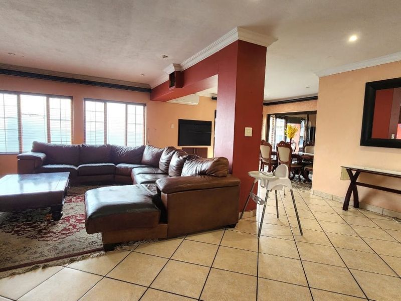 Spacious open-plan living and dining area featuring tiled flooring, coved cornicing, and recessed lighting, offering a versatile layout for family living.