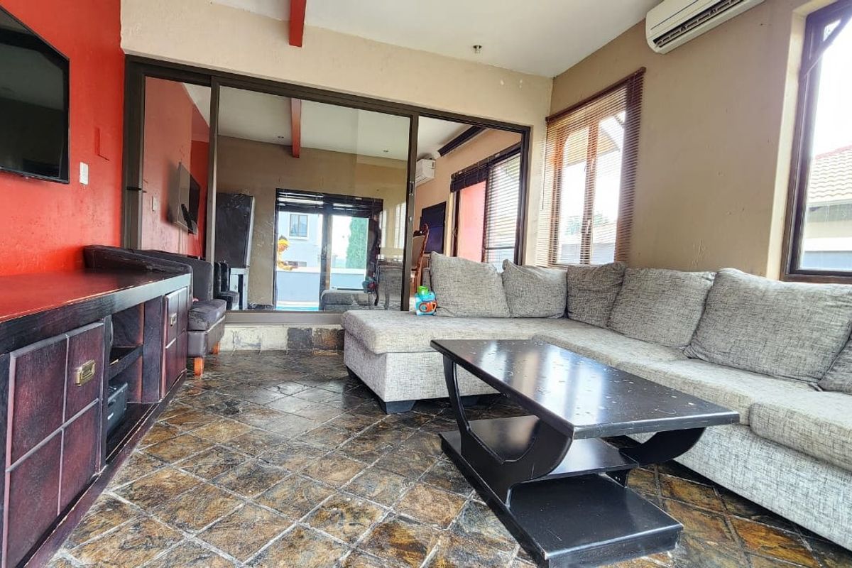 A living room featuring tiled flooring, split-system air conditioning, and large sliding glass doors that provide natural light and access to the exterior.