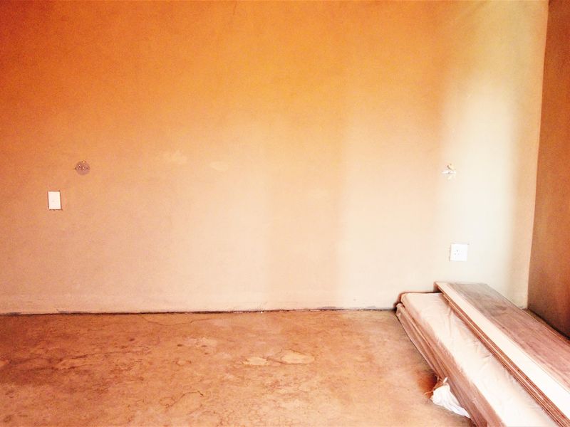 An unfinished room featuring bare walls and a concrete floor, presenting a blank canvas ready for renovation and flooring installation.