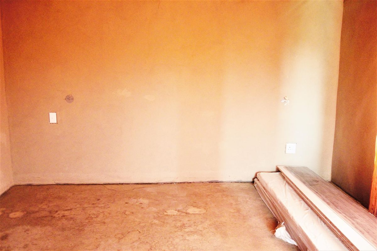 An unfinished room featuring bare walls and a concrete floor, presenting a blank canvas ready for renovation and flooring installation.
