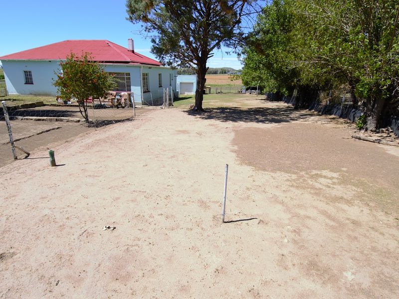 Spacious rear yard area featuring a detached garage and views of the surrounding landscape, offering significant potential for landscaping and outdoor development.