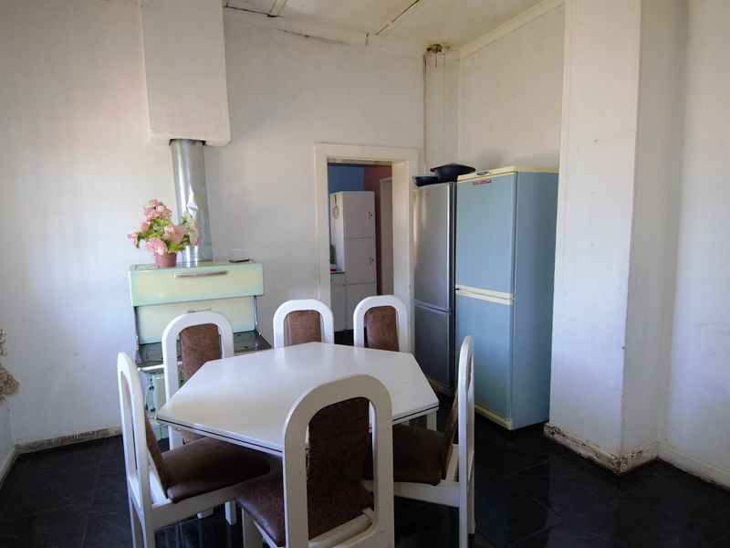 A dated kitchen area featuring a vintage stove with a flue pipe and dark tiled flooring, offering significant potential for modernization and renovation.