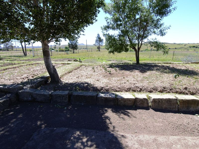 A spacious outdoor garden area featuring a stone retaining wall and open views of the surrounding landscape.
