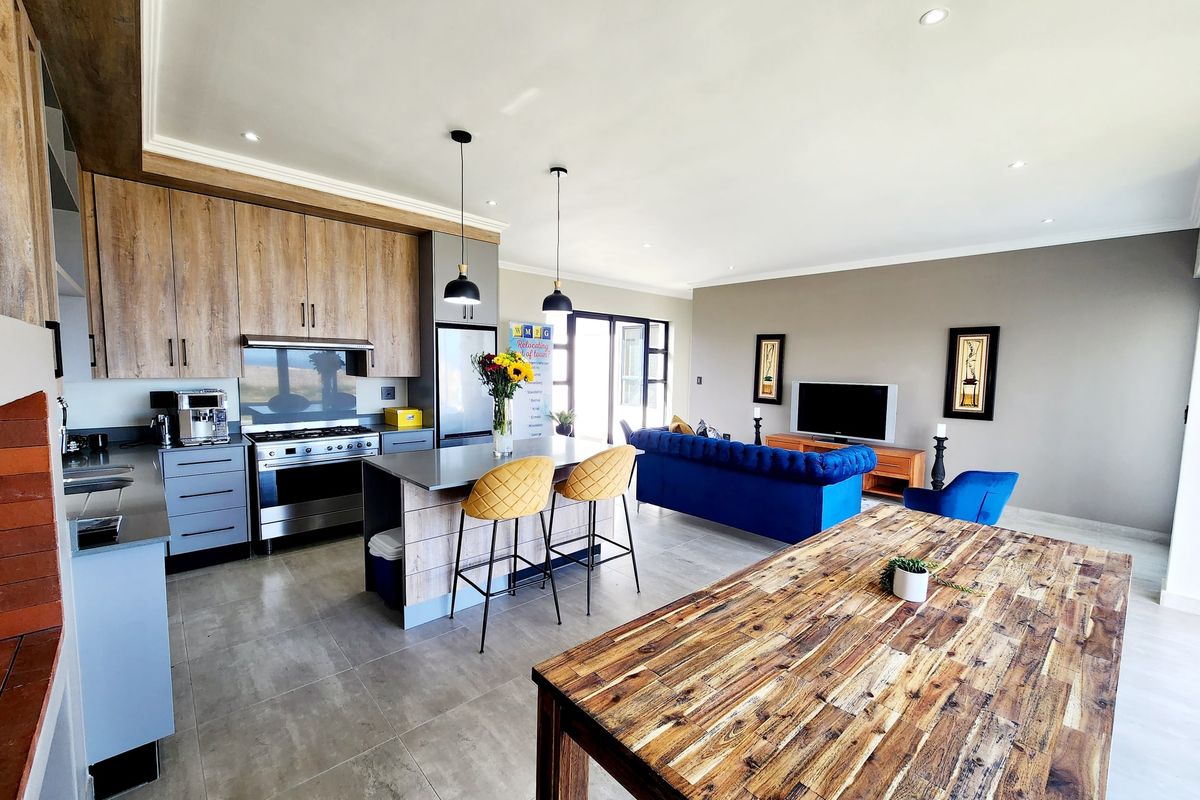 Spacious open-plan living area featuring a modern kitchen with a central island, gas stove, and seamless flow to the lounge and dining space.