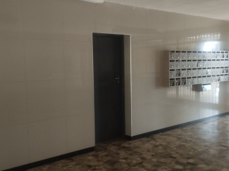 A clean apartment building entrance lobby featuring tiled walls, flooring, and a bank of wall-mounted mailboxes.