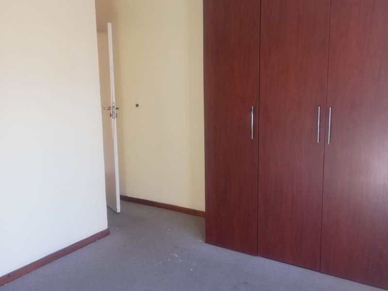 An empty bedroom featuring built-in wooden cupboards and carpeted flooring, offering a blank canvas for personalization.