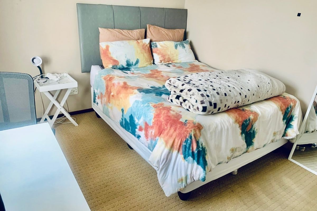 A functional bedroom featuring neutral wall tones and carpeted flooring, providing a comfortable and practical living space.