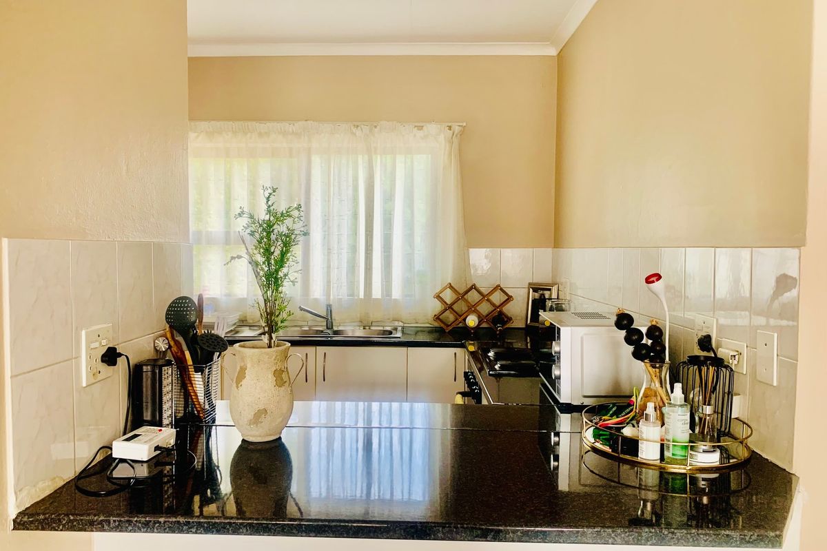 A functional kitchen featuring dark granite countertops, a stainless steel sink, tiled backsplash, and built-in cabinetry with a hob.