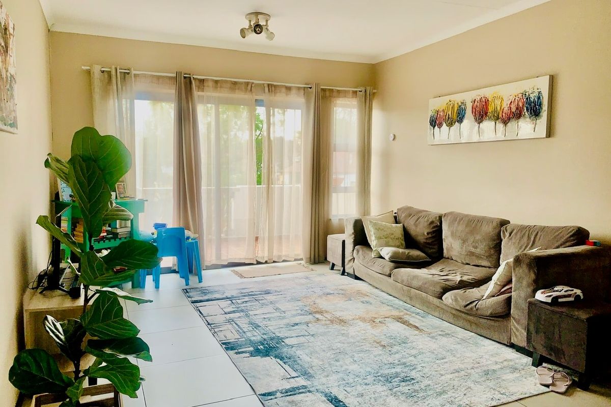 A bright living room featuring tiled flooring and a large sliding glass door that provides access to an outdoor balcony area.