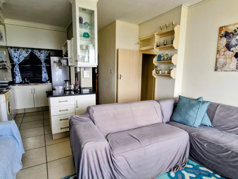 Open-plan living area featuring a compact kitchen with built-in cabinetry, granite countertops, and tiled flooring, seamlessly connected to the lounge space.