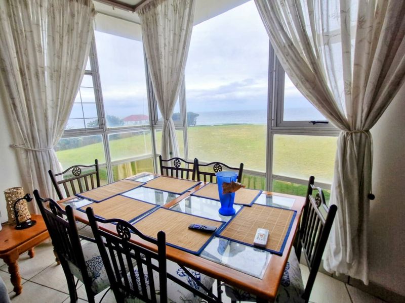 Dining area featuring large windows with expansive coastal views and tiled flooring, providing a bright and airy space for meals.