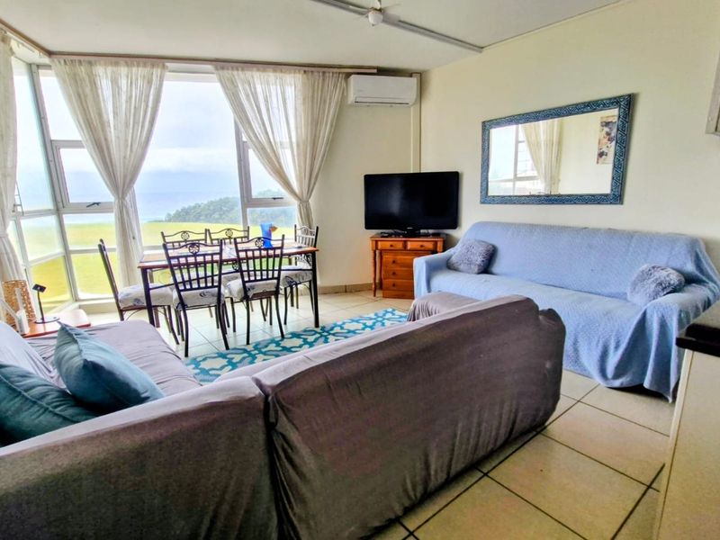 Open-plan living and dining area featuring tiled floors, split-system air conditioning, and large windows with natural light and scenic views.