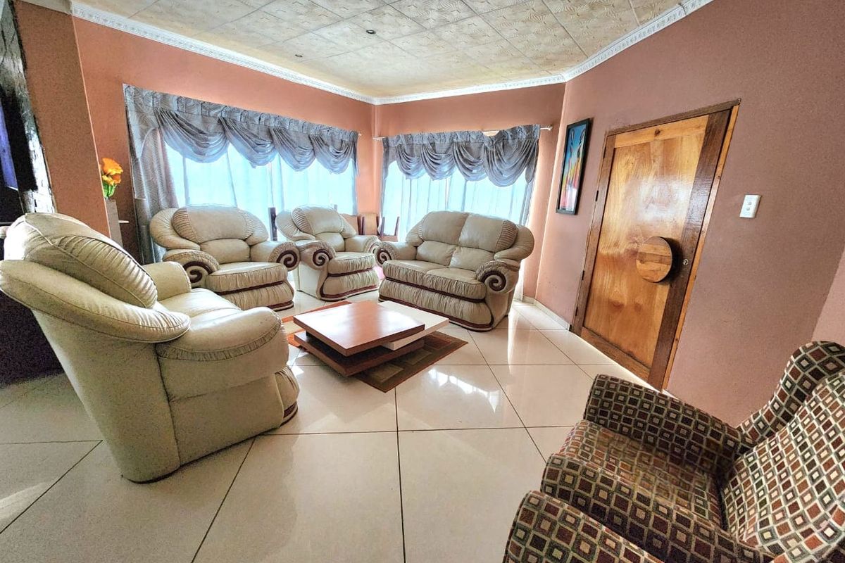 A spacious living room featuring large windows, tiled flooring, and a textured ceiling, offering a comfortable area for relaxation.