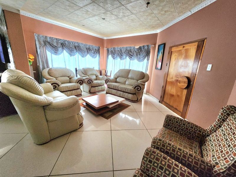 A spacious living room featuring large windows, tiled flooring, and a textured ceiling, offering a comfortable area for relaxation.