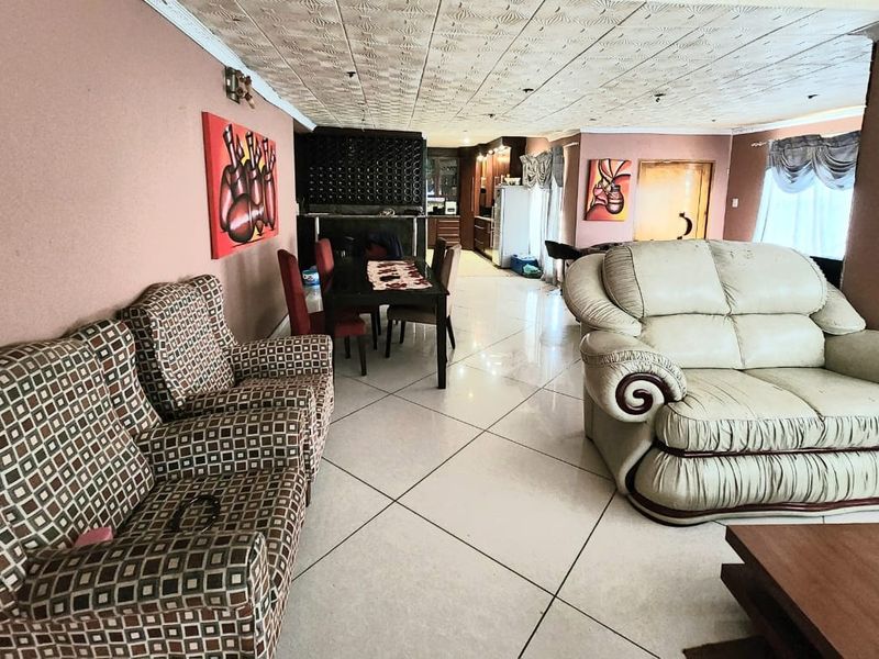 Spacious open-plan living and dining area featuring large floor tiles, a textured ceiling, and integrated kitchen cabinetry with a built-in wine rack.