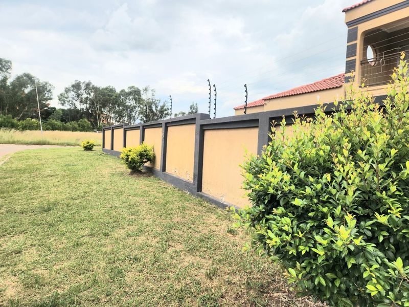 A view of the property's perimeter wall featuring integrated electric fencing and a well-maintained lawn area.