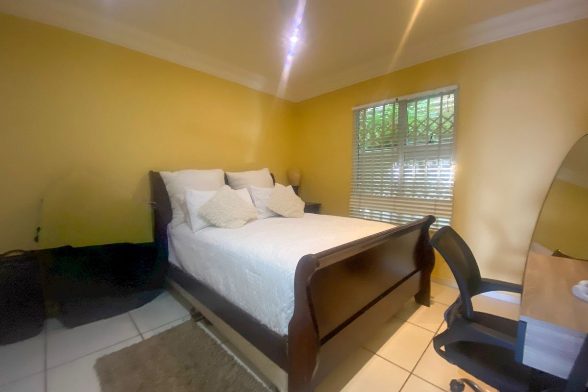 A bedroom featuring tiled flooring, cornicing, and a window fitted with security bars and venetian blinds.