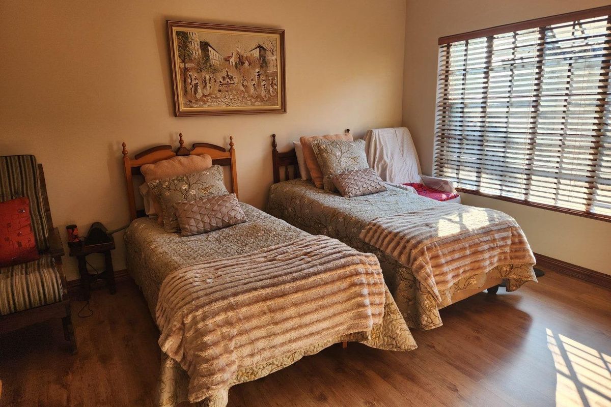 A well-lit bedroom featuring laminate flooring and venetian blinds, providing a comfortable and functional space.