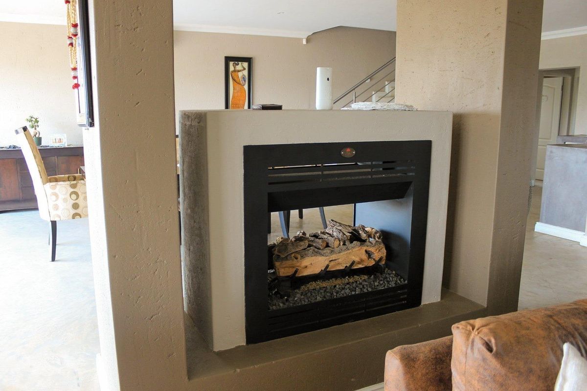 A central living area featuring a modern built-in fireplace set within a partition wall, with a staircase visible in the background.