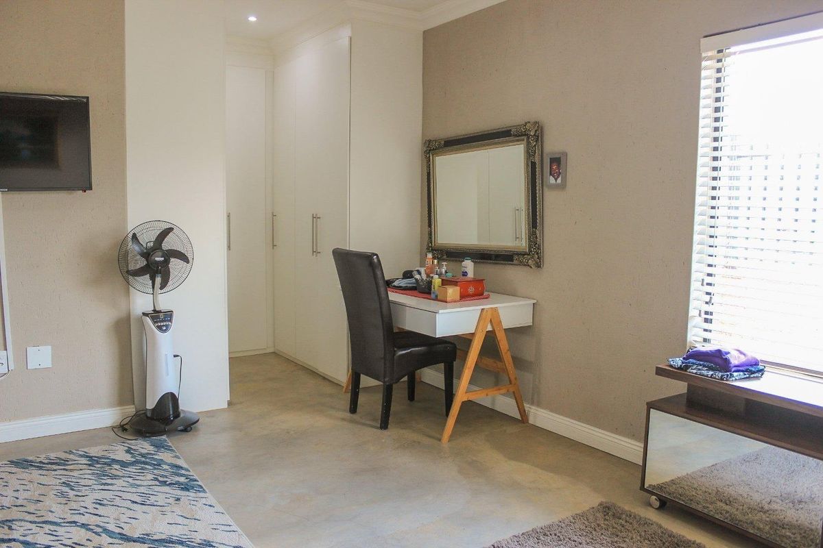 A bedroom featuring polished concrete flooring, built-in cupboards, and natural light through venetian blinds.