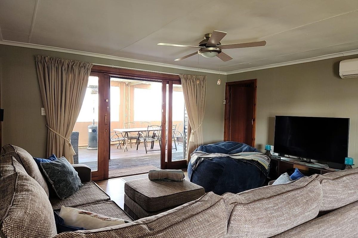 A comfortable living room featuring a ceiling fan, split-system air conditioning, and large sliding glass doors providing direct access to an outdoor patio area.