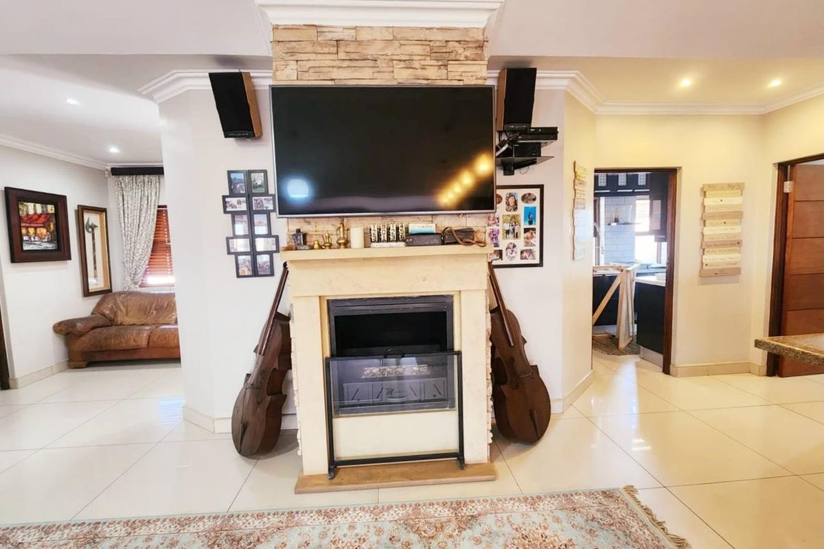 Spacious living area featuring a central stone-clad fireplace, tiled flooring, and recessed lighting, creating a warm and inviting atmosphere.