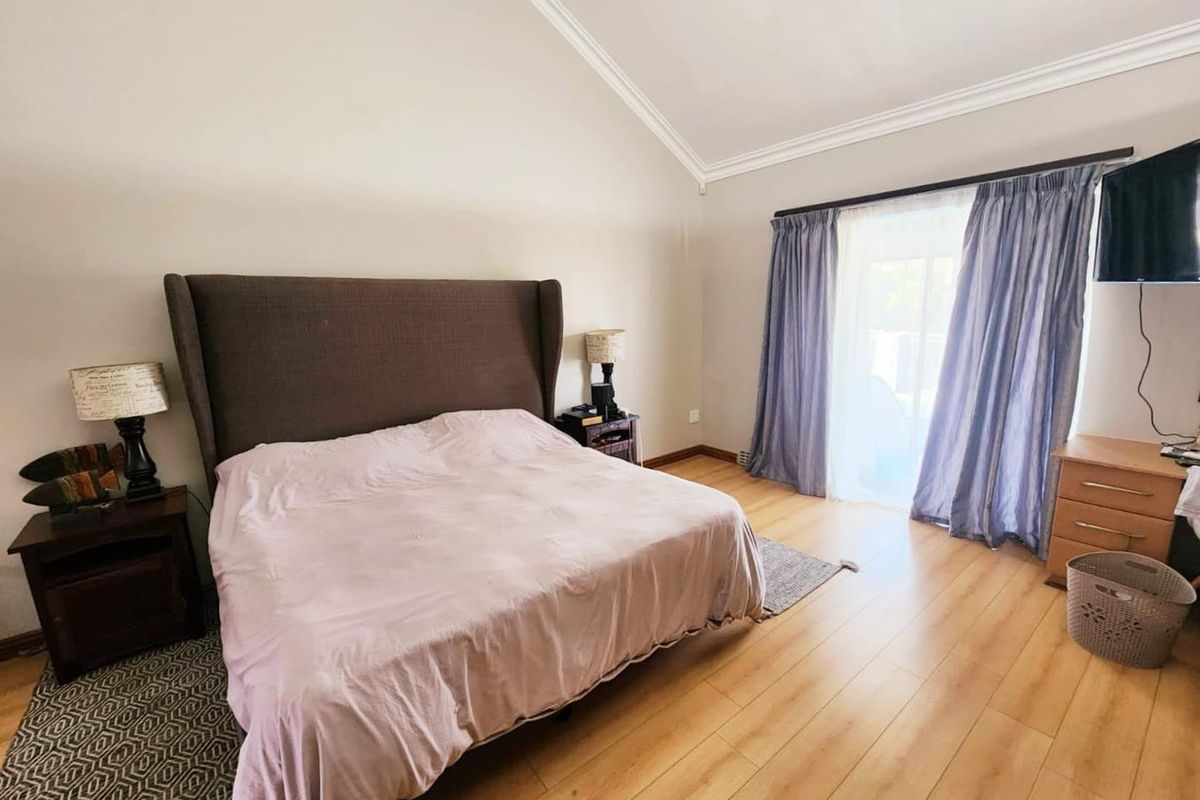 Spacious bedroom featuring vaulted ceilings, laminate flooring, and a sliding glass door providing access to the outdoors.
