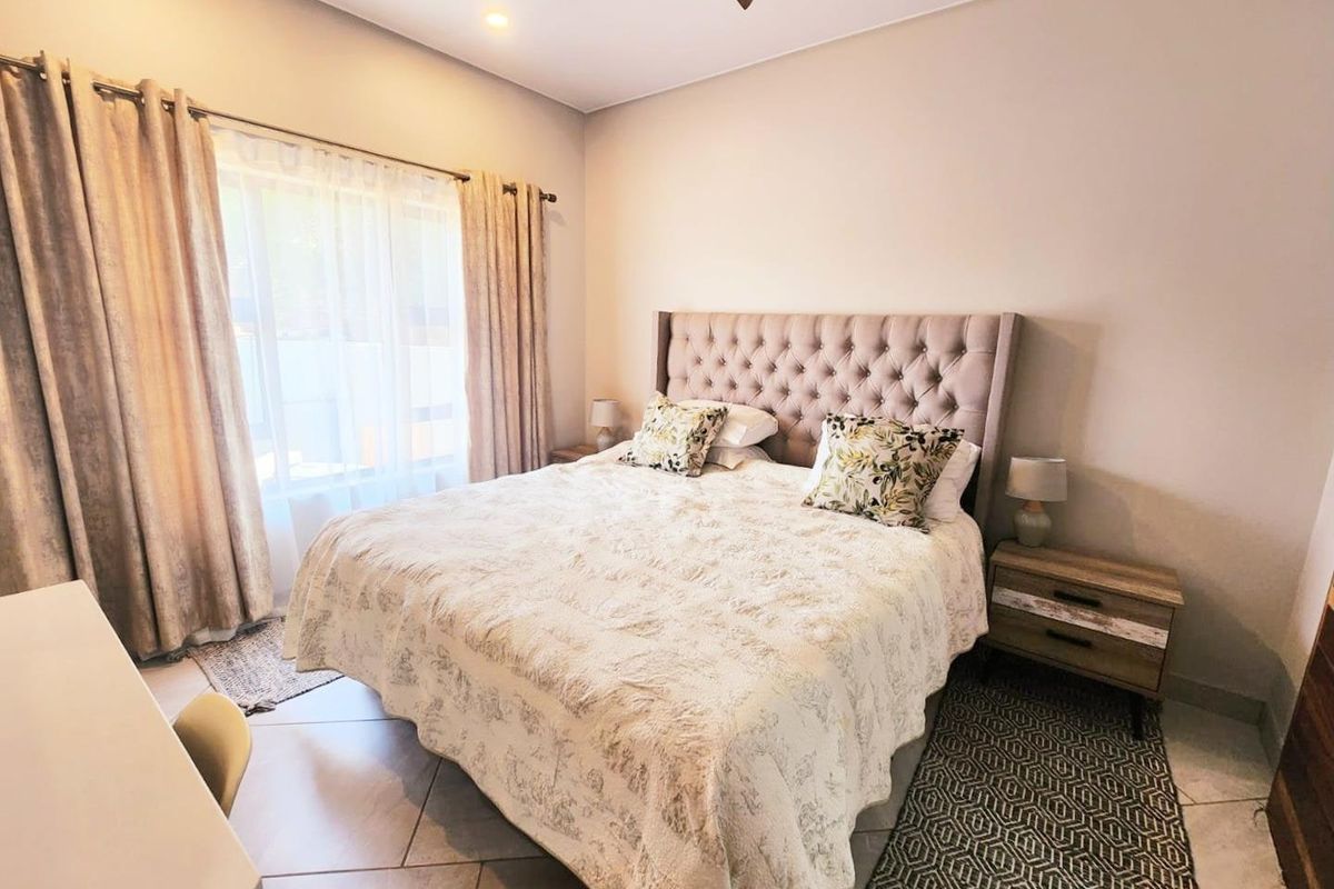A well-maintained bedroom featuring neutral wall tones, tiled flooring, and large windows that provide ample natural light.