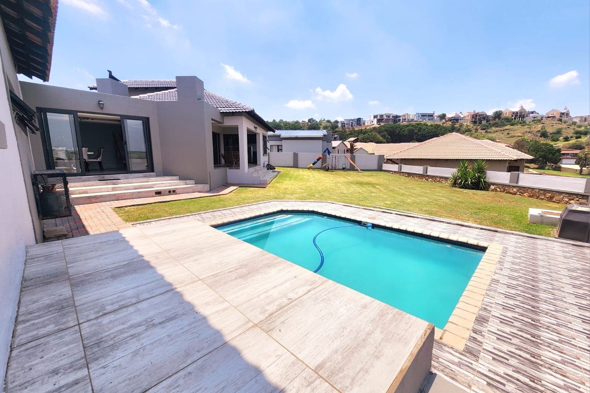 Spacious rear garden featuring a swimming pool, paved patio area, and direct access to the home through sliding doors.
