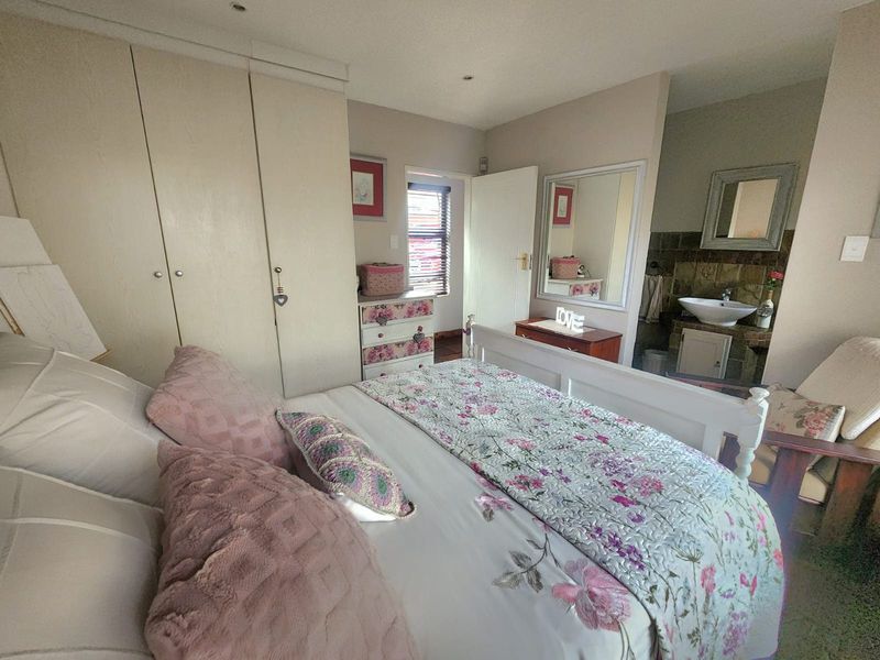 A bedroom featuring built-in cupboards and an en-suite bathroom area with a vanity basin.