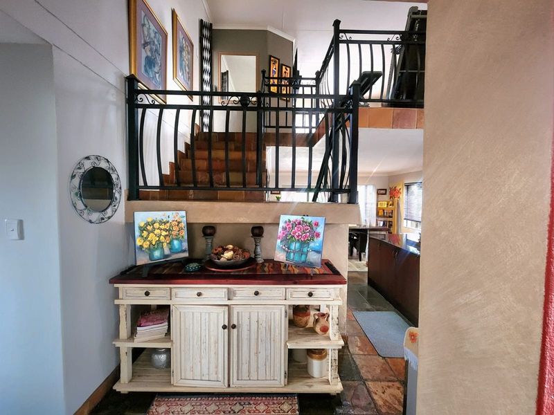 Entrance foyer featuring a staircase with decorative wrought iron balustrades, leading to an open-plan living area with tiled flooring.