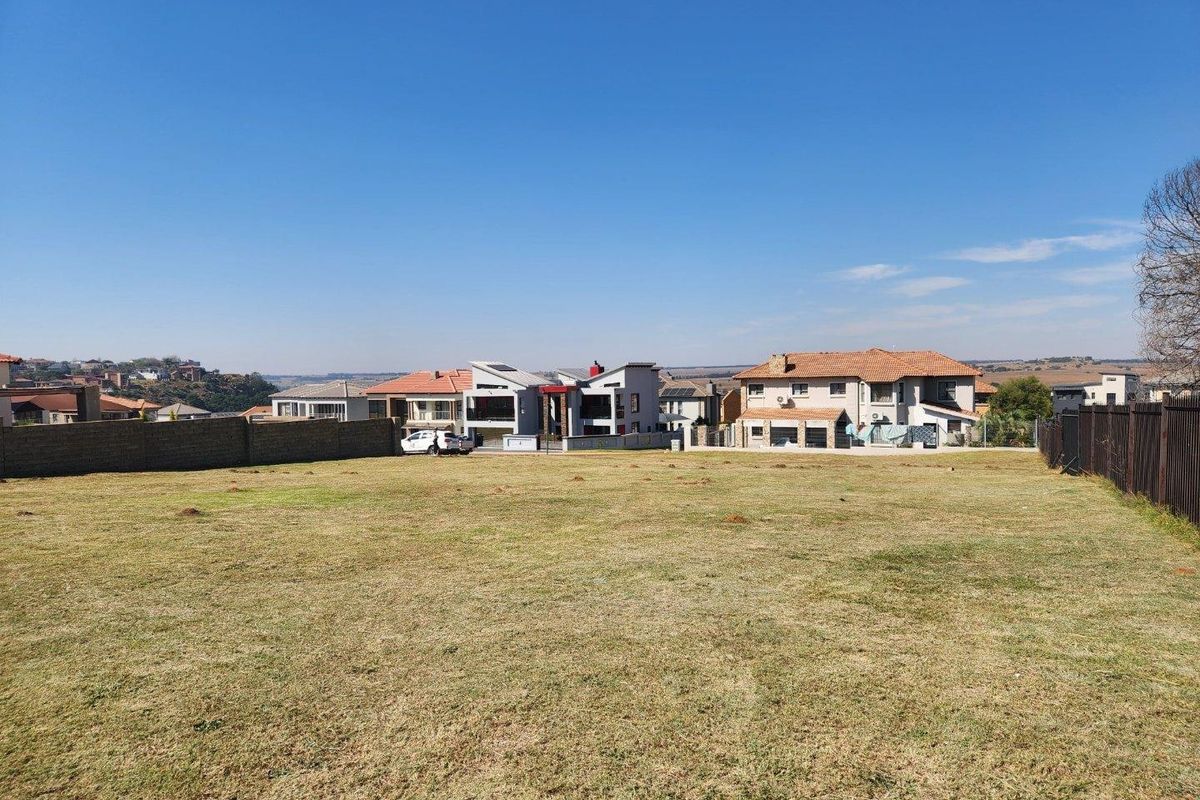 A vacant residential plot of land featuring established boundary walls and surrounding suburban residential development.