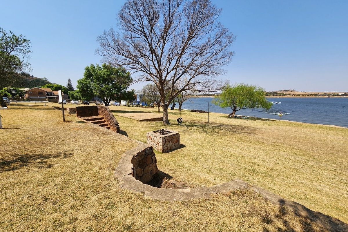 Expansive waterfront garden area featuring a stone fire pit, brick stairs, and direct access to the lake.