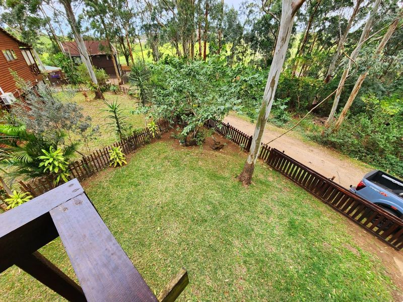 Elevated view of a private rear garden featuring a timber picket fence, mature trees, and a wooden balcony railing overlooking the yard.