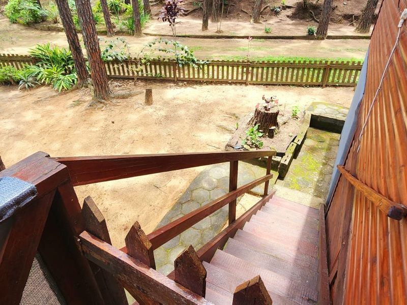 An elevated view of a wooden staircase leading down to a rear garden area with stone paving and a picket fence.