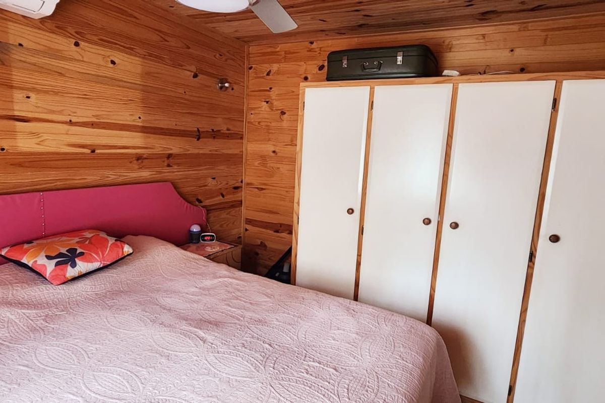 Bedroom featuring warm timber wall paneling, a built-in wardrobe with white doors, and a ceiling fan.