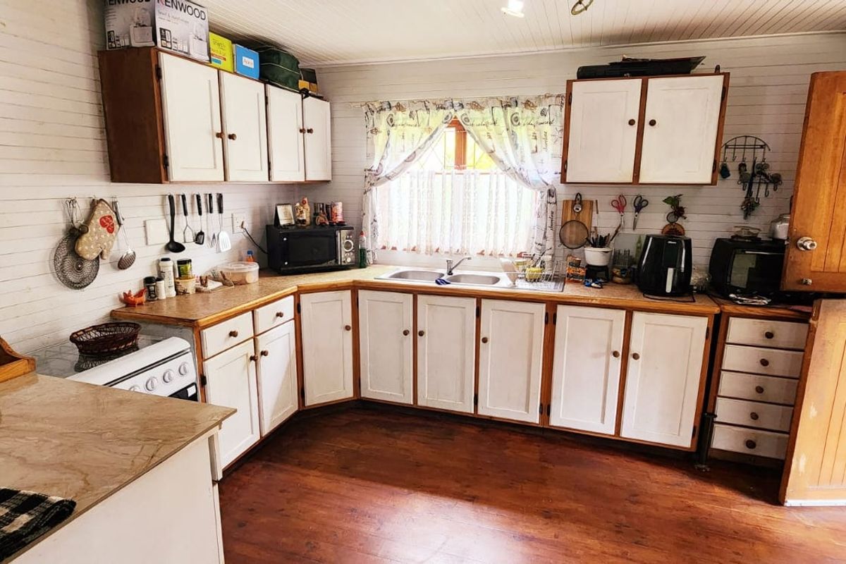 A functional kitchen featuring timber cabinetry, laminate countertops, a double bowl sink, and a classic stable door, with timber wall paneling throughout.