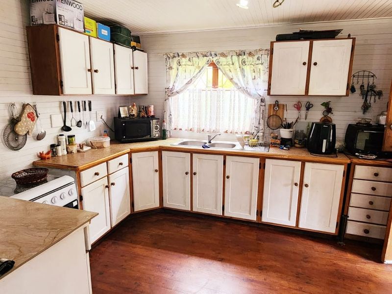 A functional kitchen featuring timber cabinetry, laminate countertops, a double bowl sink, and a classic stable door, with timber wall paneling throughout.