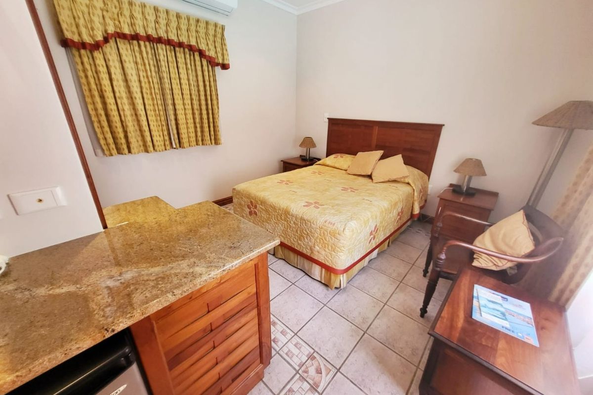 A bedroom featuring ceramic tiled flooring, a split-system air conditioner, and a built-in wooden vanity unit with a granite countertop.