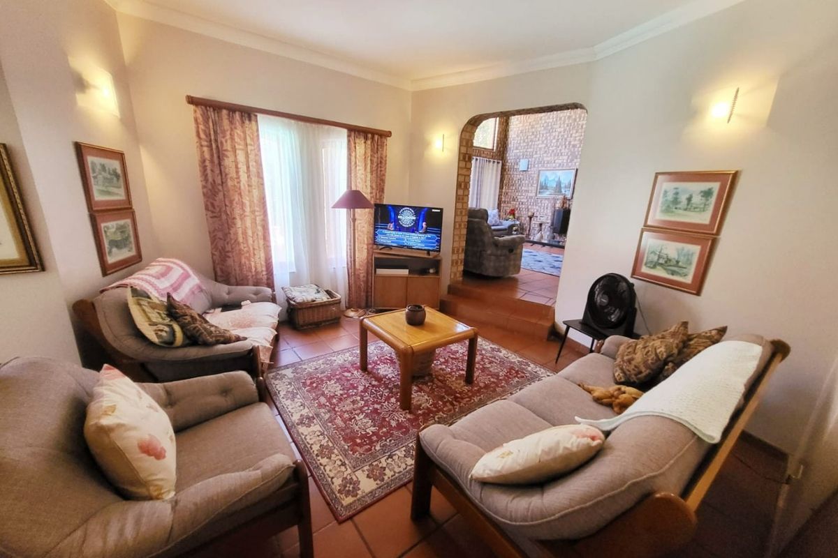 A cozy living room featuring terracotta floor tiles, an arched doorway leading to an adjacent space, and warm wall sconce lighting.