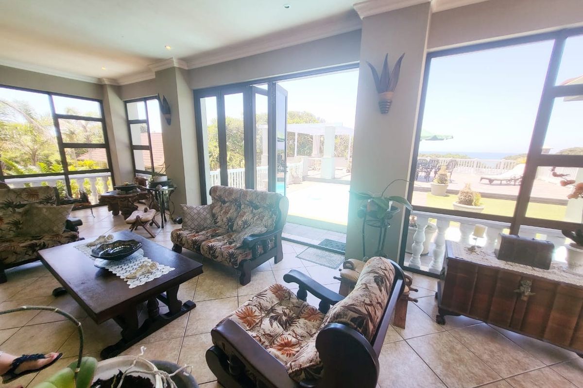 Spacious living room featuring large aluminium windows and stacking doors that provide seamless access to the outdoor patio and pool area.