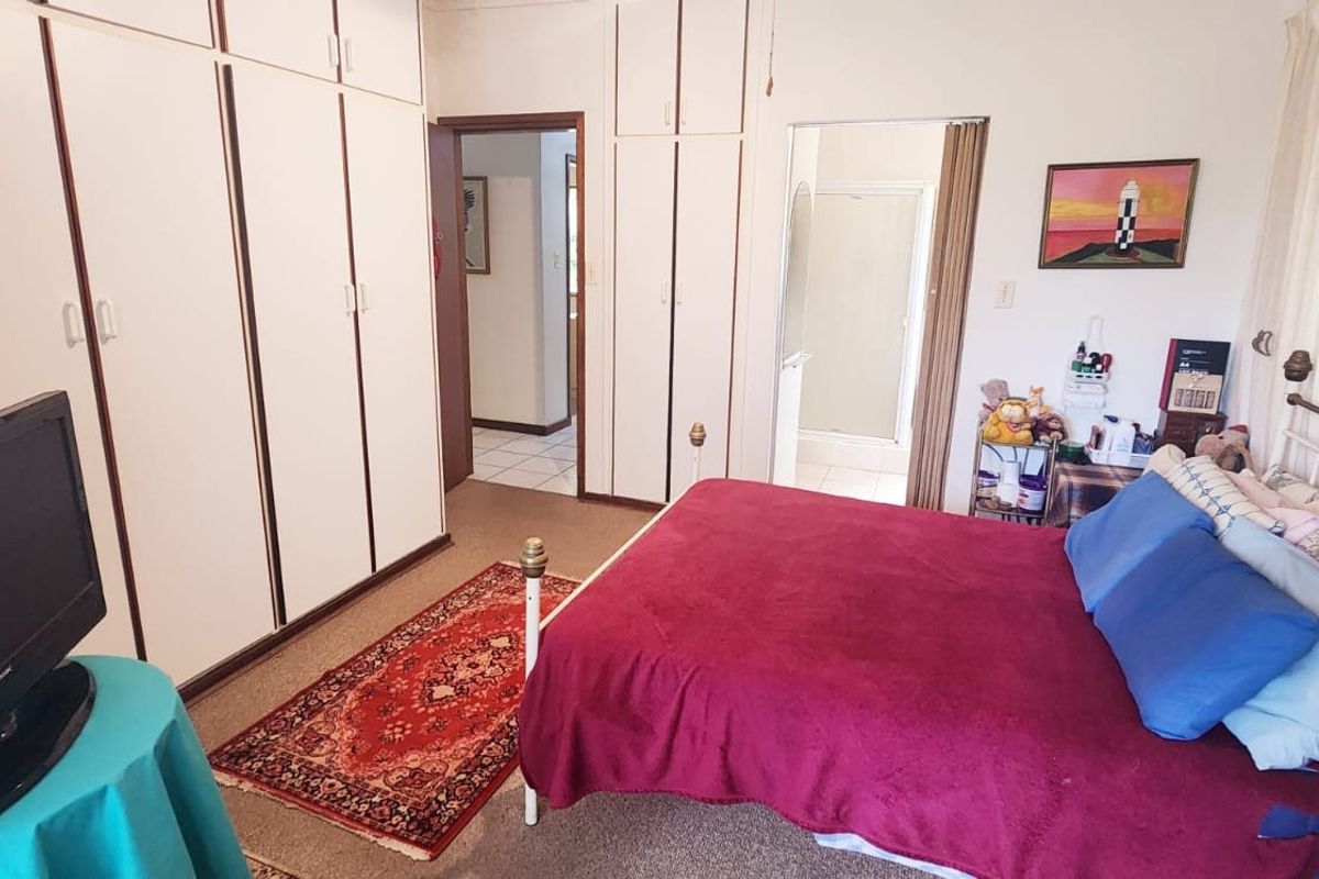 A functional bedroom featuring extensive built-in cupboard storage and direct access to an en-suite bathroom.