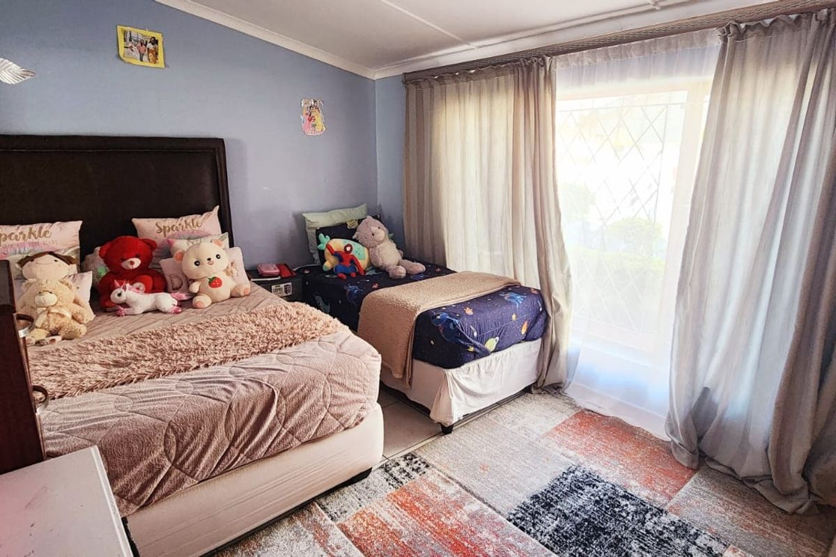 A bedroom featuring tiled flooring and a large window with security gate, providing natural light and access to the exterior.