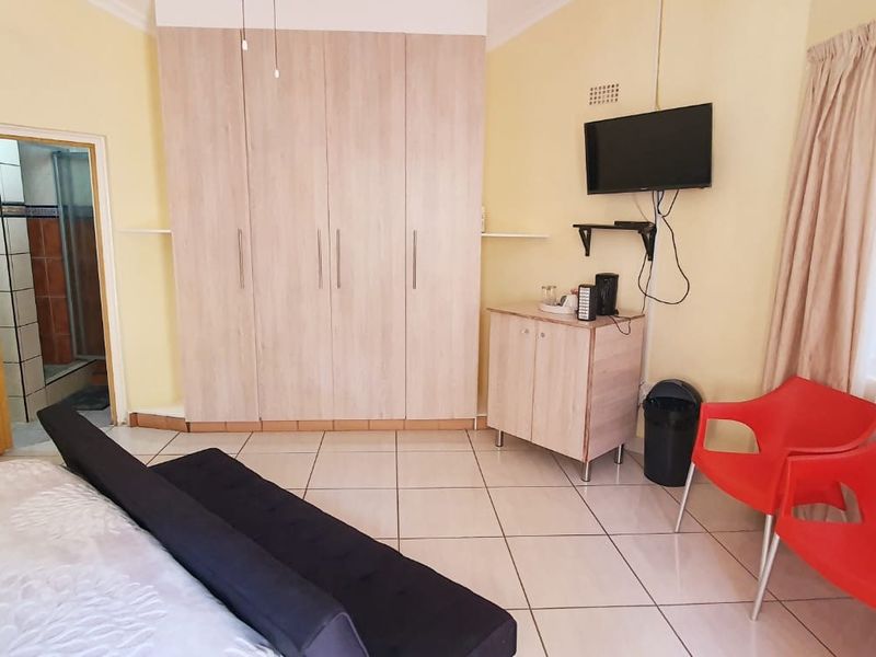 A bedroom featuring built-in cupboards, tiled flooring, and direct access to an en-suite bathroom.